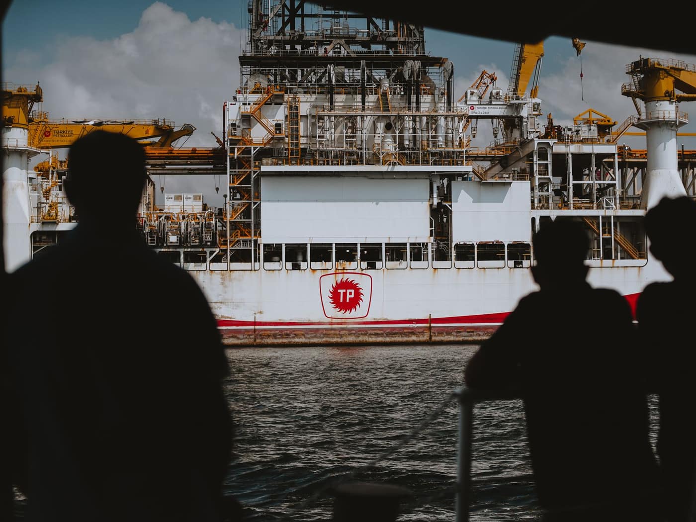 Site team silhouetted against an offshore drilling rig